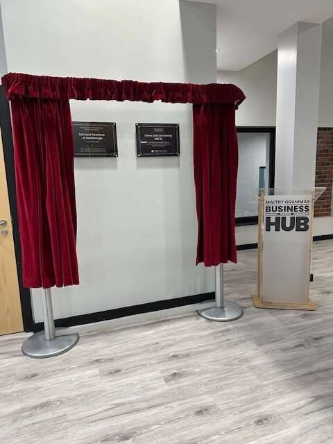 Two plaques framed by a red curtain.