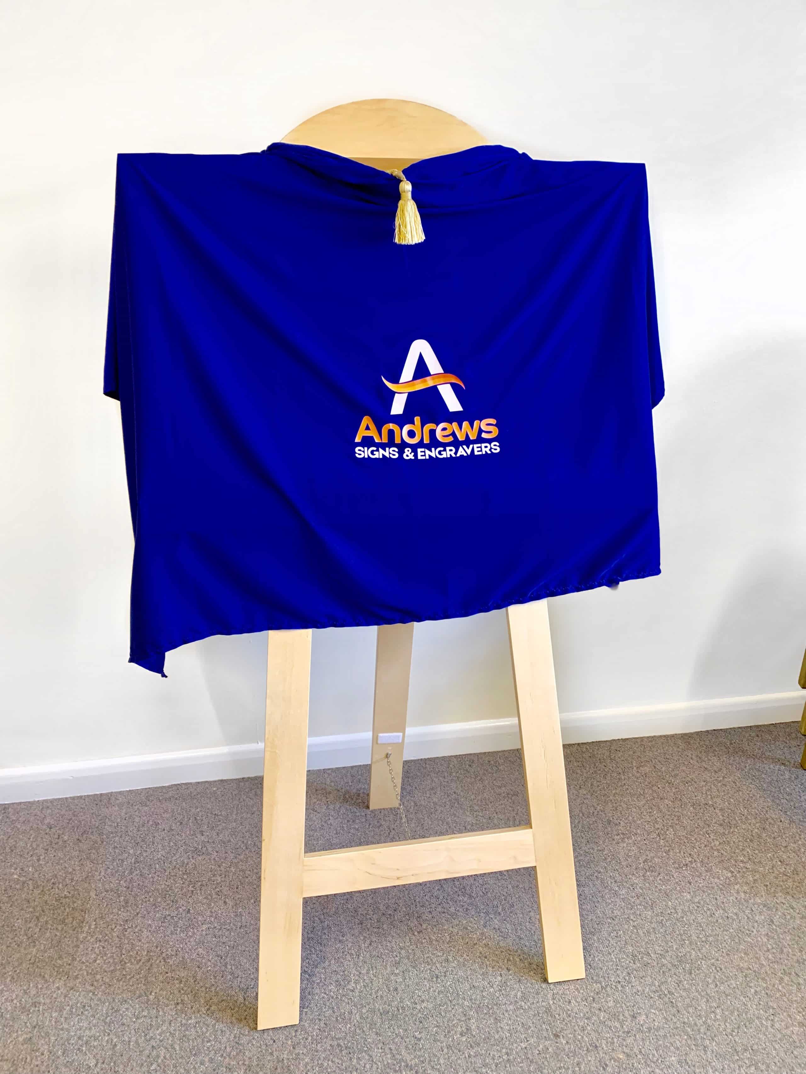 A blue drape with the Andrews Signs logo covering an easel.