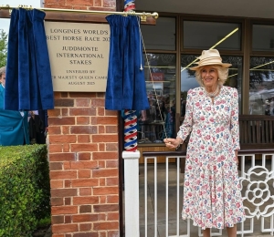 A woman having pulled the curtain pull, revealing a plaque.