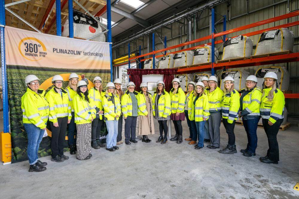 A group of people wearing hard hats and hi-vis jackets, smiling at the camera.